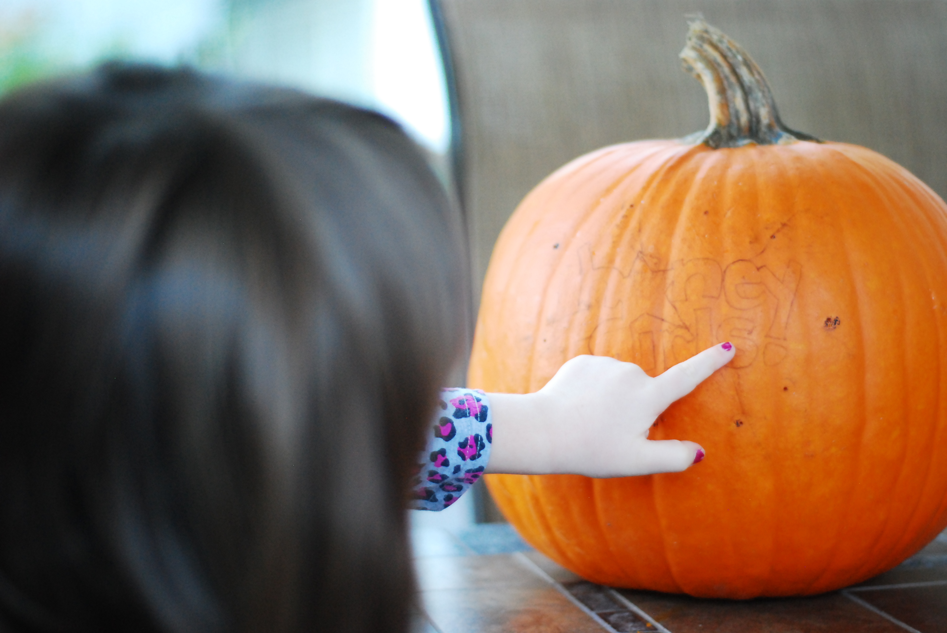 Young child inspects design blueprint on a pumpkin before carving